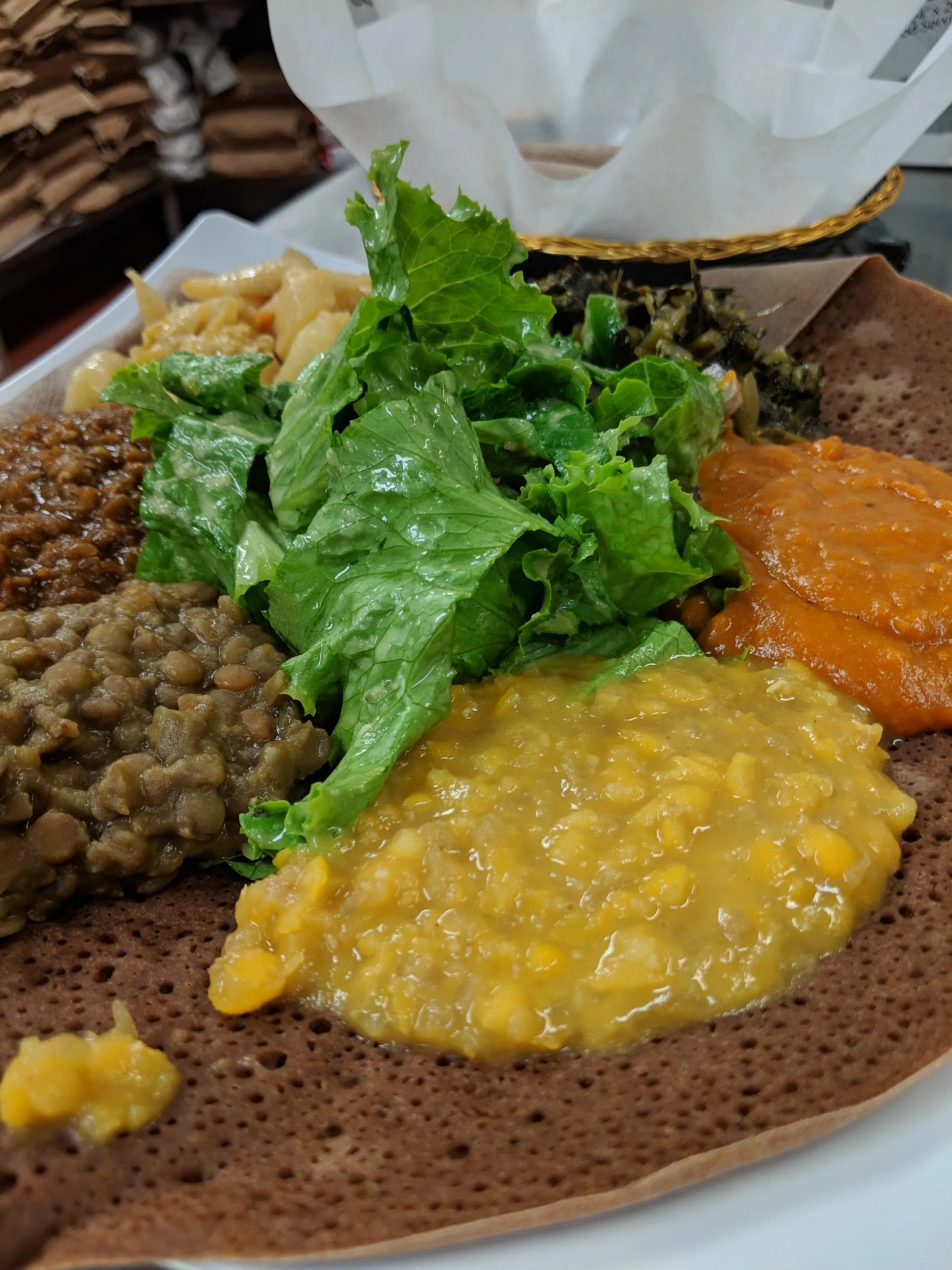 A vegetarian combination arranged over injera